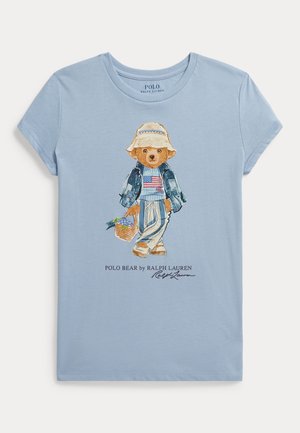 Svetlomodré tričko s krátkym rukávom s maľovaným medveďom oblečeným v džínsovej bunde, pruhovaných nohaviciach a slamenom klobúku, ktorý drží košík.
