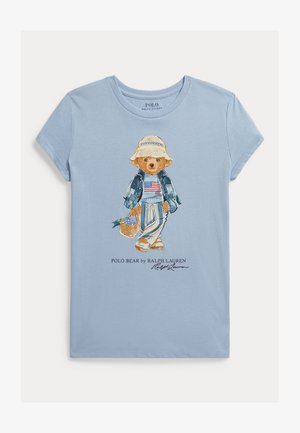 Ανοιχτό γαλάζιο κοντομάνικο μπλουζάκι με ζωγραφισμένη αρκούδα που φοράει μπουφάν από τζιν, ριγέ παντελόνια και καπέλο για τον ήλιο, κρατώντας ένα καλάθι.