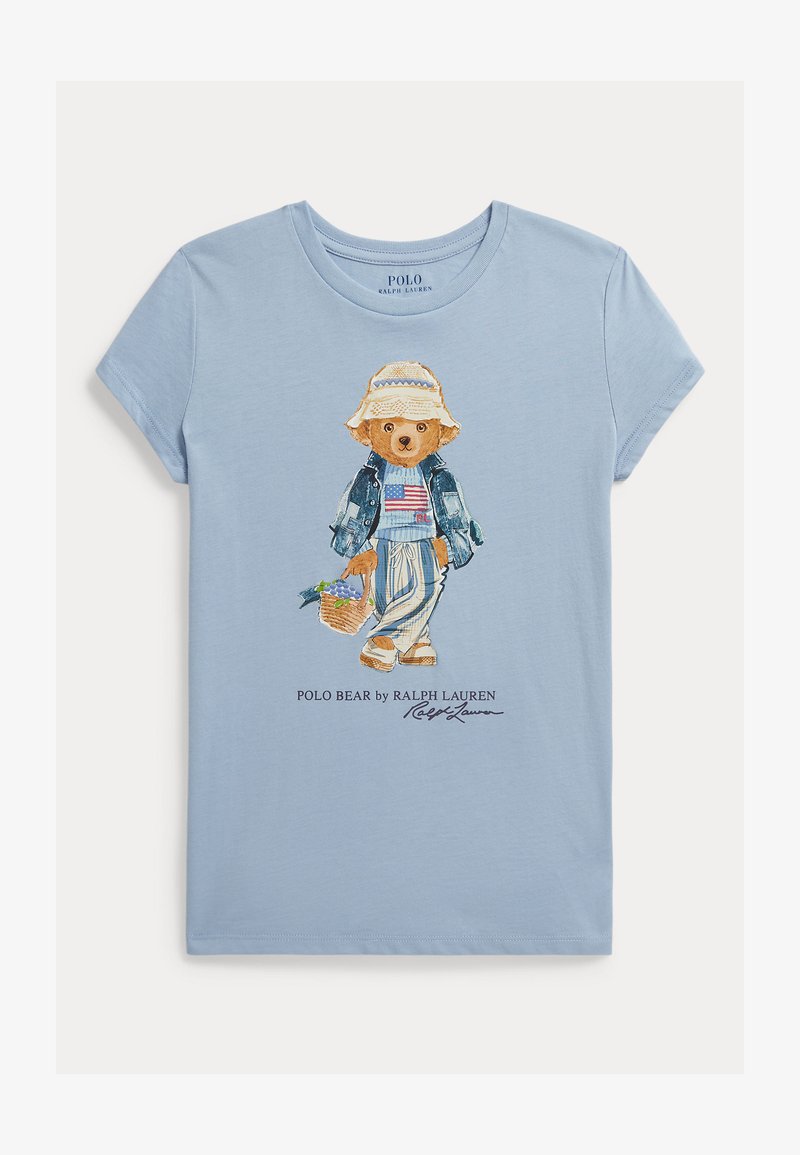 Ανοιχτό γαλάζιο κοντομάνικο μπλουζάκι με ζωγραφισμένη αρκούδα που φοράει μπουφάν από τζιν, ριγέ παντελόνια και καπέλο για τον ήλιο, κρατώντας ένα καλάθι.