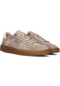 Hellebeige Wildledersneaker mit einem cremefarbenen Akzent an der Ferse, beigen Schnürsenkeln und einer braunen Gummisohle. Dezente Markenkennzeichnung an der Seite.