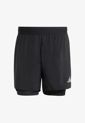 Pantalones cortos deportivos negros con una capa exterior suelta y pantalones cortos interiores ajustados. Presentan una textura suave y un logotipo reflectante sutil en el lateral.
