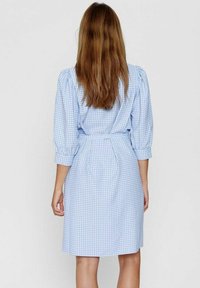 Vestito a quadri blu e bianchi con maniche puff a 3/4, vita legata e un design strutturato. Tessuto liscio e orlo alla ginocchia.