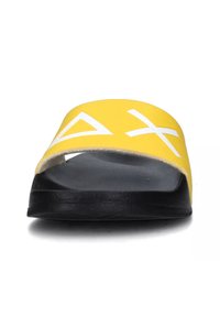 Infradito gialli con una fascia larga caratterizzata da motivi geometrici bianchi, suola in gomma nera e superficie liscia.