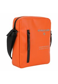 Oranžová syntetická kabelka přes rameno s přední kapsou na zip, černými akcenty a tištěnými detaily. Má plochý, obdélníkový design.