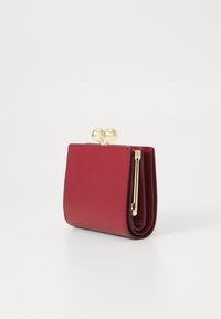 Red faux leather wallet with a clasp closure featuring two metallic spheres, a minimalist design, and a compact rectangular shape.
