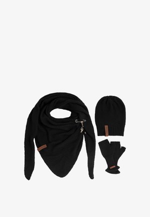 Gehaakte zwarte sjaal met franjes, cirkelvormige drukknoopdetail; bijpassende zwarte beanie en zonder vingertoppen handschoenen met leren accenten. Alle items hebben een textuur.