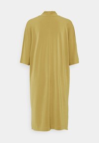 Musztardowożółta sukienka do kolan z krótkimi rękawami i wysokim kołnierzem, widziana od tyłu na jednolitym tle.