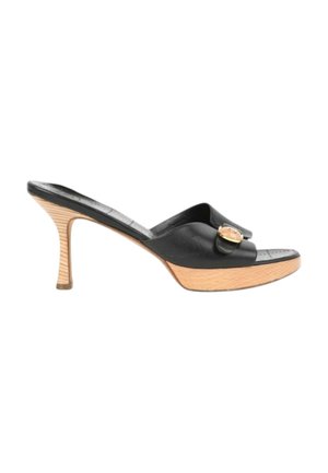 Mule en cuir noir à bout ouvert avec un talon stiletto en bois de hauteur moyenne et une boucle ronde dorée sur la bride avant.
