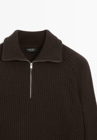 Maglione a costine di colore marrone scuro con una zip a metà e un ampio colletto ripiegato.