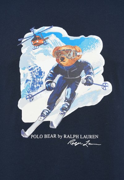 Novi mornarski T-shirt s grafikom medvjeda na skijama u naočalama za skijanje, s helikopterom iznad i planinama u pozadini. Ispod teksta piše "POLO BEAR by RALPH LAUREN."