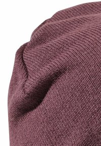 Knitted beanie in a muted burgundy color. Features ribbed texture with soft, fine yarn. Cuffed edge adds dimension.