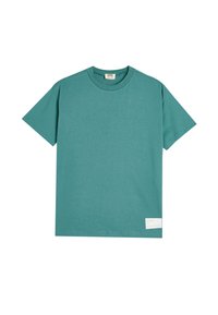 Camiseta de algodón color teal con mangas cortas, cuello redondo y una etiqueta rectangular en la parte inferior que muestra el texto "el océano".