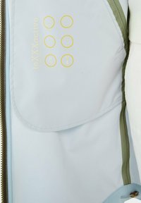 Jasnoniebieska kurtka z recyklingowaną membraną. Ozdobiona oliwkowo-zielonymi akcentami, zawiera żółte ikony wskazujące na wodoodporne i oddychające właściwości.