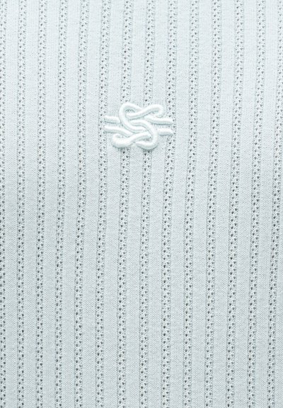 Λευκό ύφασμα με κάθετες υφασμάτινες ρίγες και ανάγλυφο κεντημένο σχέδιο κόμπου στο κέντρο της επιφάνειας.