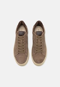 Baskets en suède marron avec un design bas, bout rond et fermeture à lacets à l'avant. Présentent un accent de talon en cuir marron foncé. Semelles crème.