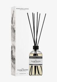Bâtonnets parfumés dans une bouteille en verre transparent avec un capuchon noir. Des tiges noires verticales s'élèvent de la bouteille. La boîte blanche présente un design abstrait en noir et blanc.