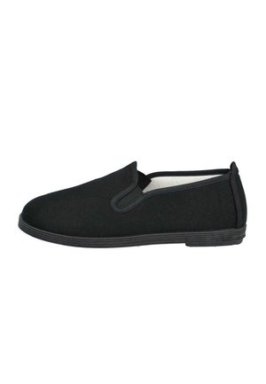 Zapato negro tipo slip-on con suela de goma plana y paneles laterales elásticos, diseñado para uso informal.