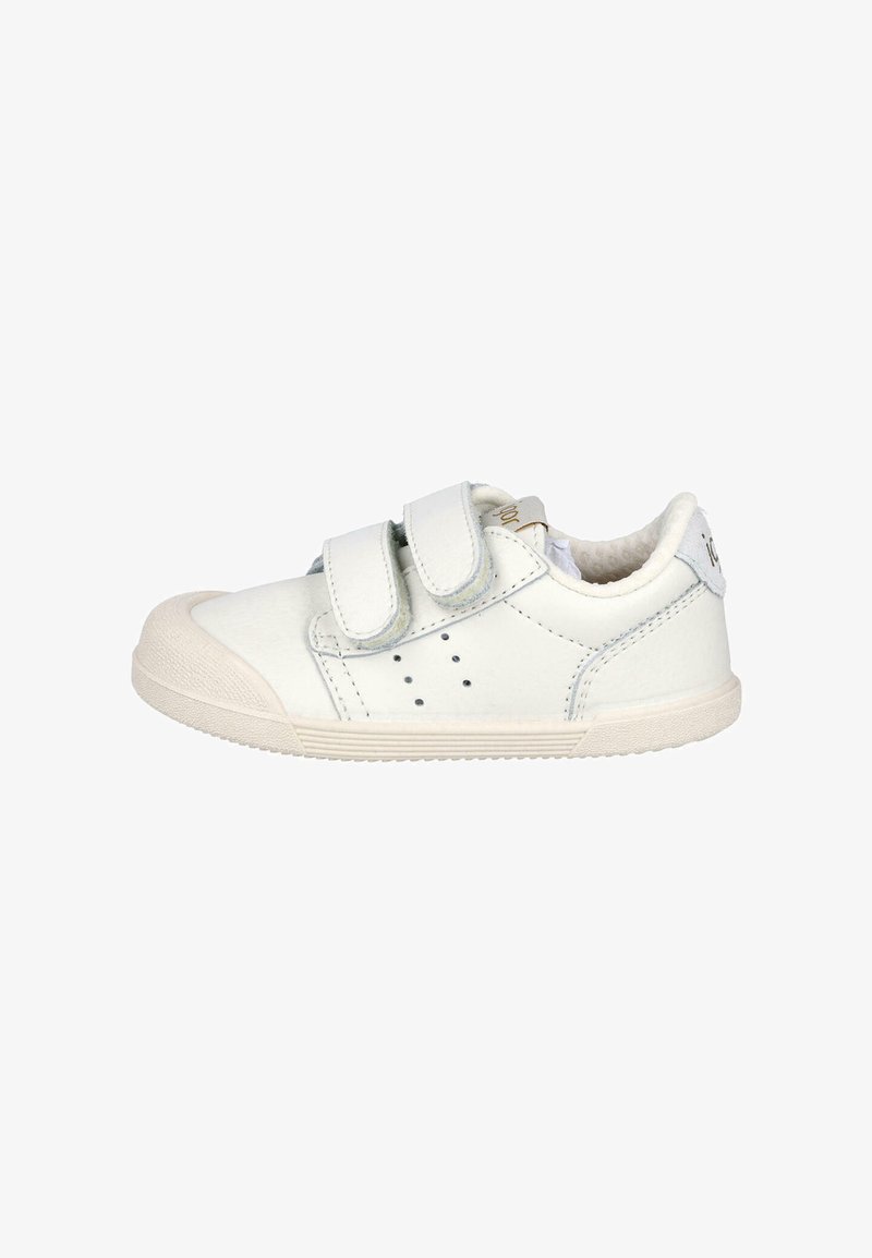 Zapatillas blancas para niños con dos correas de velcro, suela de goma beige, cuello acolchado y pequeñas perforaciones en el lado para ventilación.