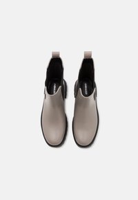 Paire de bottines grises avec semelles noires et languettes de tirage, vues de dessus sur un fond blanc.