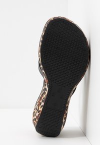 Chaussure à imprimé léopard avec une semelle en caoutchouc noire texturée, un design incurvé et une tige en matériau lisse. Marques de taille visibles sur la semelle.