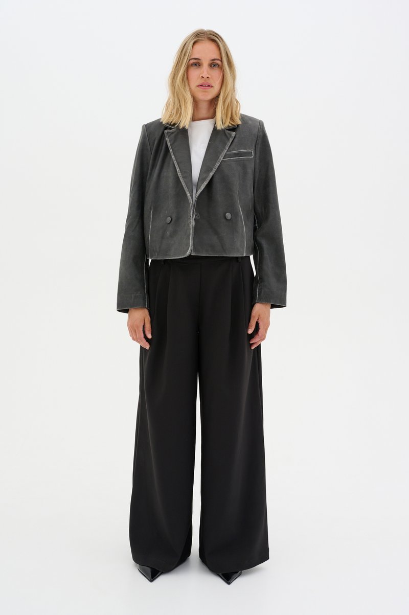 Gray cropped jacket with a notched collar, two buttons, and a subtle sheen, paired with high-waisted black wide-leg trousers.