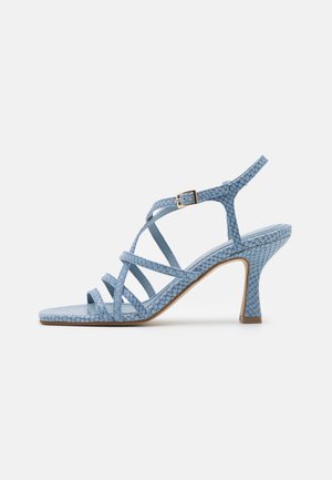 Lichtblauwe sandalen met hoge hakken en bandjes, met een gestructureerd patroon, vierkante neus, verstelbare enkelriem en smalle hak op een witte achtergrond.