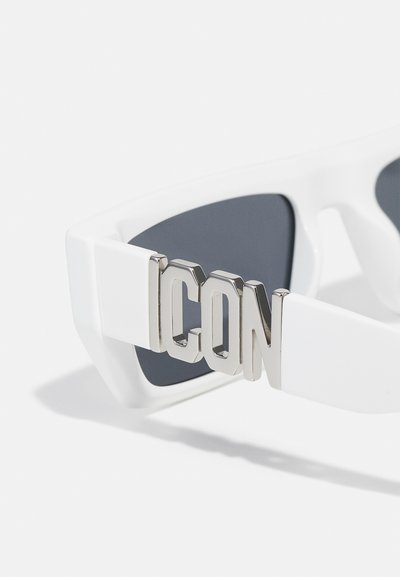 Gafas de sol blancas con forma angular, lentes oscuros y un acento plateado con el logo "ICON" en el lateral. Montura de plástico suave con detalle metálico.
