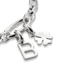Silberne Armbandkette mit einem großen Gliederdesign, mit einem charm in Form eines großen "B" und einem charm in Form eines Kleeblatts. Glatte, reflektierende Oberfläche.