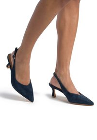 Décolleté slingback in suede blu navy con punta affilata, tacco a cono piccolo e fibbia decorativa sulla cinghia alla caviglia. Texture liscia e design elegante.