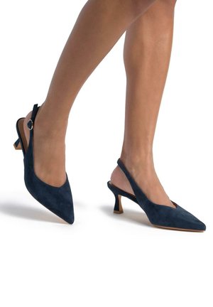 Décolleté slingback in suede blu navy con punta affilata, tacco a cono piccolo e fibbia decorativa sulla cinghia alla caviglia. Texture liscia e design elegante.