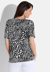Zwart-witte top met korte mouwen en een patroon geïnspireerd door dieren, met onder andere zebra- en luipaardmotieven, met een zachte textuur.