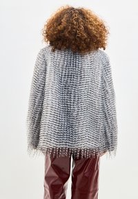 Cardigan tricotat texturat de culoare gri deschis, cu margine din franjuri, având un model în dungi. Asortat cu pantaloni din piele lucioasă burgundy, în contrast.