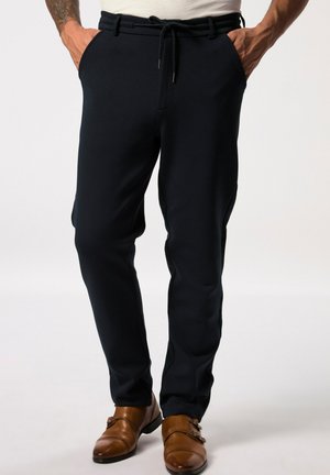 Navy jogger pants in soft fabric with elastic waistband, decorative drawstring, and side pockets; paired with brown leather shoes.