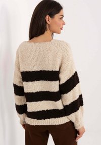 Gestreifter Pullover aus cremefarbenem und dunkelbraunem Strick, oversized Passform, strukturierte Garnqualität, weite Ärmel und ein rundes Dekolleté. Lässiger Stil.