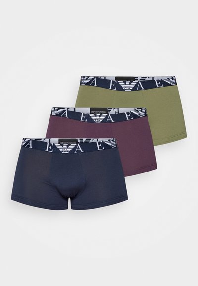 Trīs vīriešu bokseršortu pāri tumši zilā, olīviešu zaļā un bordo krāsā. Katrs no tiem ir aprīkots ar elastīgu jostasvietu ar zīmola logo rakstu.