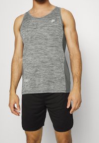Canottiera sportiva grigia con texture mélange, pannelli laterali in grigio scuro e un piccolo logo bianco sul petto, abbinata a pantaloni corti neri.