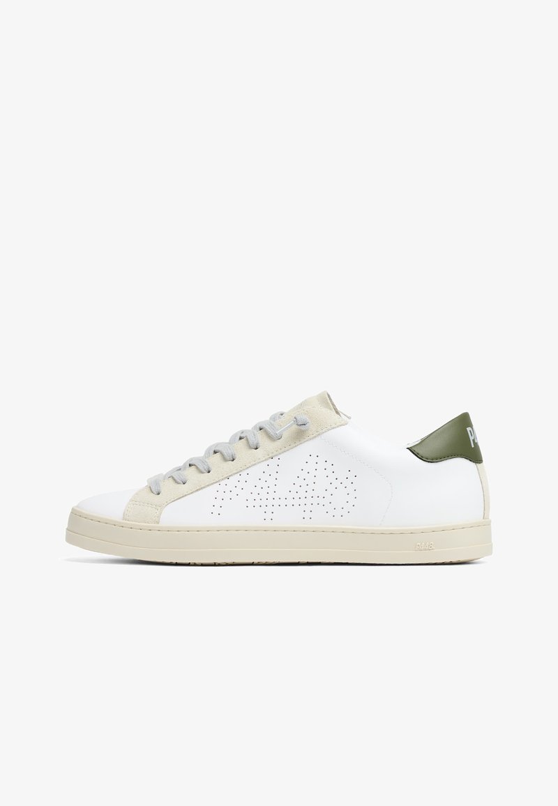 Baskets basses blanches avec empiècement en suède beige pour les lacets, design perforé sur le côté, semelle beige et languette de talon verte marquée d’un texte blanc.