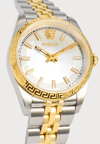 Ανδρικό ρολόι χειρός Versace σε δίχρωμο ασημί και χρυσό με χρυσούς δείκτες ώρας, λογότυπο Μέδουσας στις 12 η ώρα και γεωμετρικό σχέδιο στη στεφάνη και το καντράν.