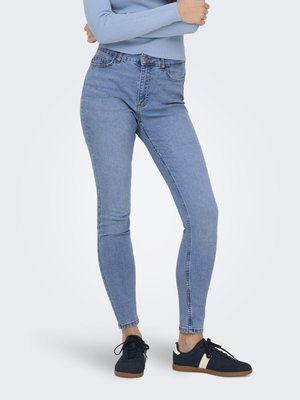 Light blue skinny jeans with a high waist, featuring five pockets and a button closure. Worn with black sneakers and a light blue top.