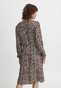 Šaty s leopardím vzorom z ľahkého materiálu, s dlhými rukávmi, elastickým pásom a voľným strihom. Vzoru dominujú zemité tóny.