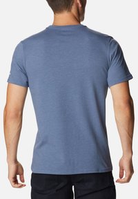 Camiseta azul de manga corta hecha de una tela suave, con un escote redondo y un corte relajado. Costuras visibles y una textura suave.