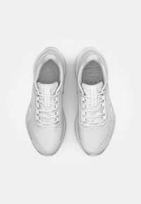 White athletic shoes with a mesh upper, padded tongue, and laces. The design features subtle accents and a textured pattern on the sole.