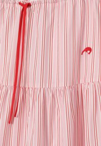 Tissu rose avec des rayures rouges et blanches verticales, couture froncée, cordon rouge et petit détail brodé de flamant rose rouge.