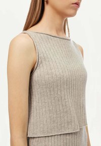 Ljusgrå ärmlös topp med vertikal ribbad textur, båtformad halsringning och lagerutsmyckad nederkant. Tillverkad av mjukt, lätt tyg.