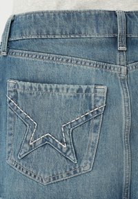 Kerge sinise värviga fadeeritud denimhud, mille tagakotil on tähekujuline õmblusdetail ja standardne vöökoha disain.