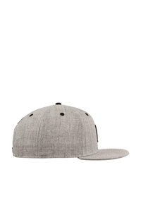 Grå baseballcap laget av teksturert stoff, med flat skjerm, svarte ventilasjonsøyne og en svart detaljerte lapp på siden.