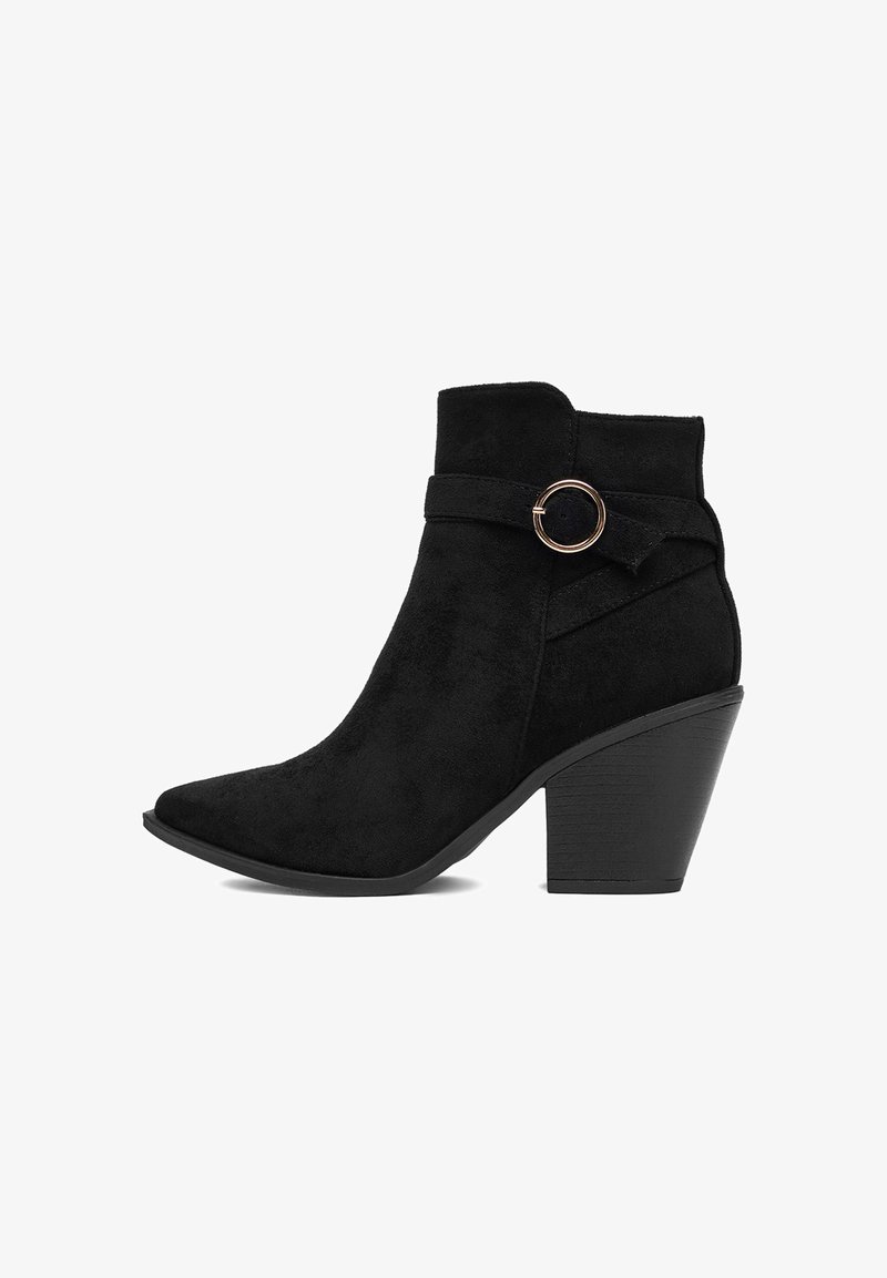 Melnas zamšādas potīšu zābaki ar smailu purngalu, bloku papēdi un dekoratīvu siksnu ar apaļu zelta sprādzi uz ārējās puses.