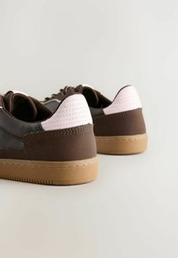 Sneaker marroni con accenti rosa, vista dal retro, che evidenzia i materiali testurizzati e la suola a contrasto.