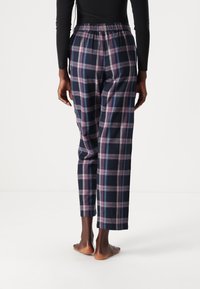 Pantalons de pyjama en tartan avec un waistband élastique, ornés de motifs à carreaux bleu marine, rose et bleu clair. Coupe ample et longueur courte.