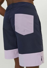 Costumi da bagno da uomo con corpo blu navy, orlo viola chiaro e una tasca posteriore. Realizzati in tessuto morbido con vita piatta.